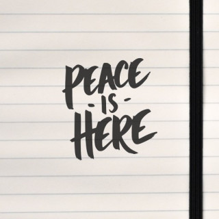 Bold brushstroke lettering declares “PEACE IS HERE” in a minimalist black-on-white design, radiating calm and presence.