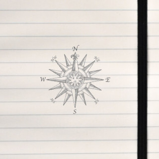 A classic black‑and‑white compass rose featuring a sun face at the center and ornate directional points.